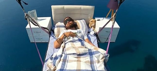 Yamaç paraşütüne bağlanan yatağa gökyüzünde uzandı